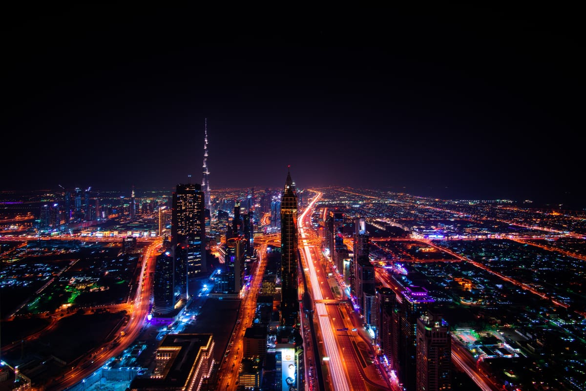 Downtown Dubai at night from the air, the Burj Khalifa above ribbons of traffic light