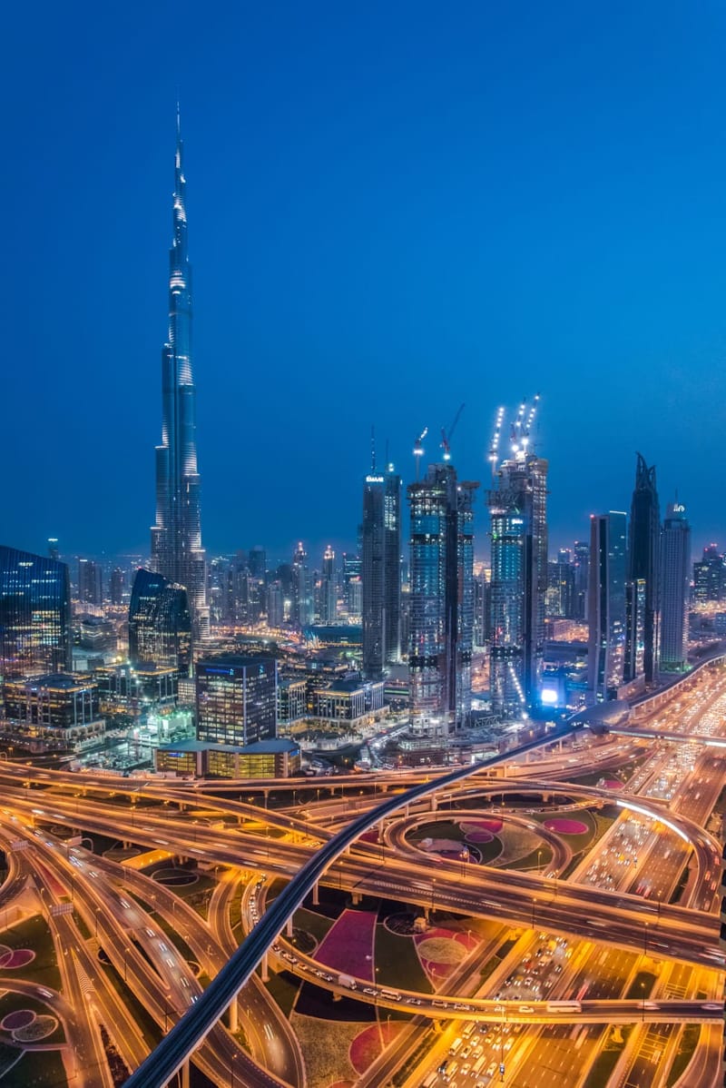 Downtown Dubai at night from the air, the Burj Khalifa standing above the lit towers of Downtown