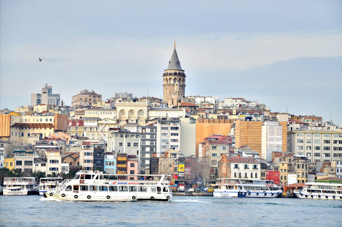The Galata Tower above the rooftops of Istanbul, ferries on the Golden Horn