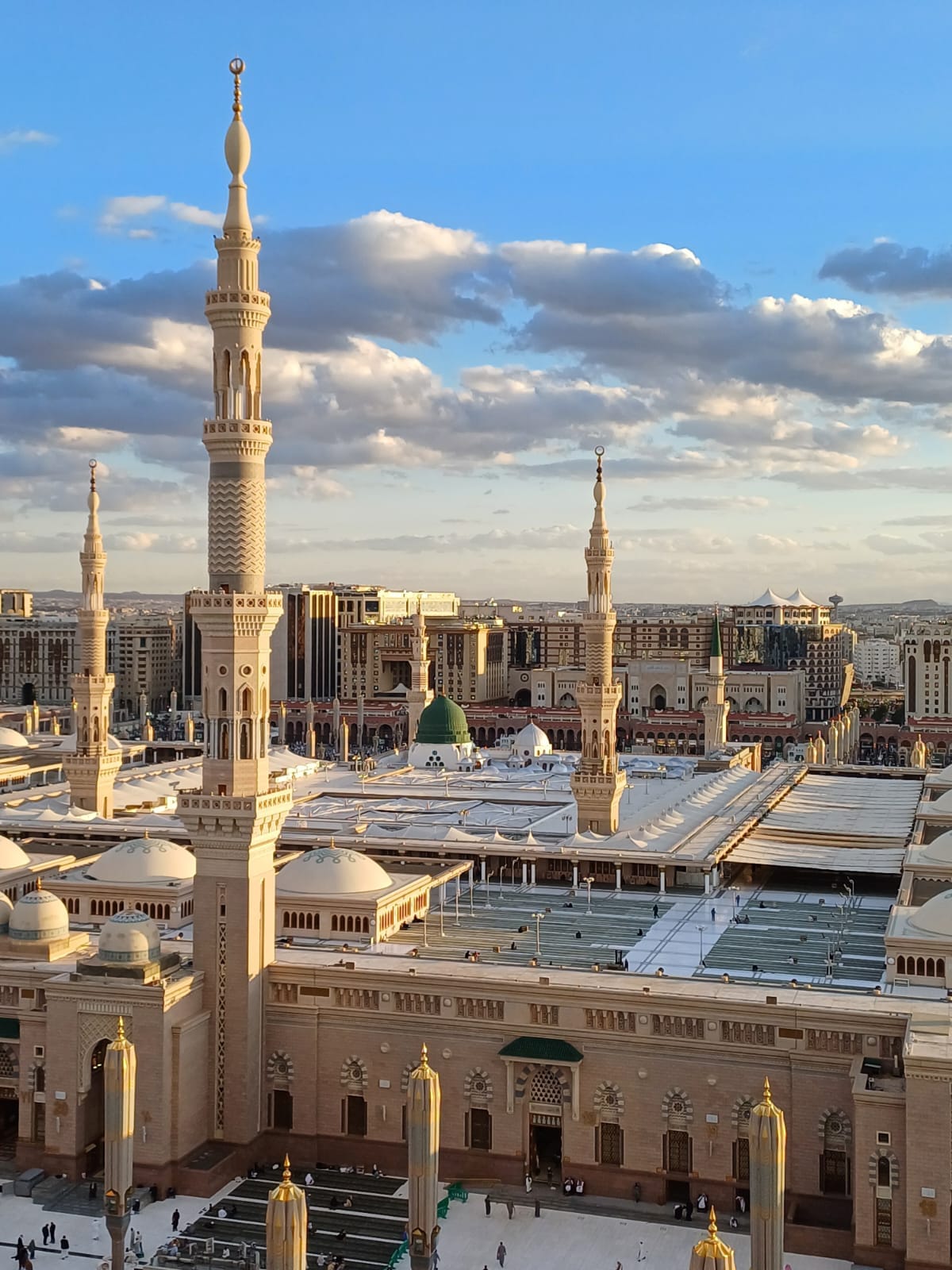 Al-Masjid an-Nabawi in Madinah in the late afternoon, its green dome and minarets above the courtyard canopies