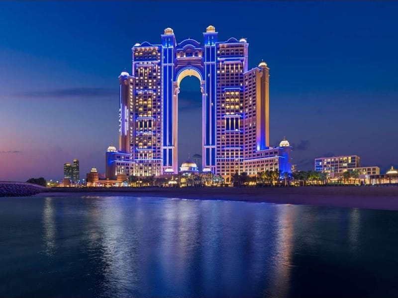 The floodlit arch of the Rixos Marina Abu Dhabi reflected in the water at blue hour