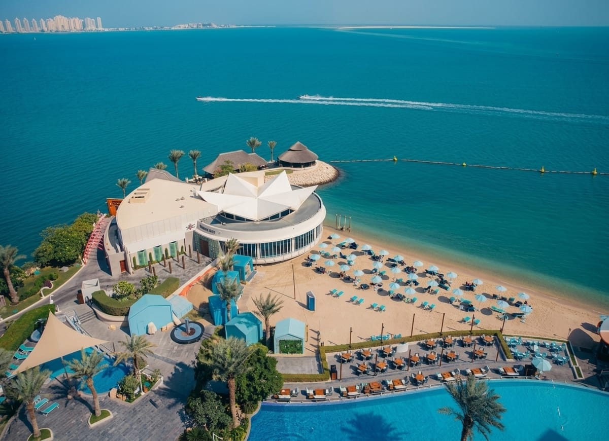 The beach and pools of the Hilton Doha from the air, the Gulf turquoise beyond them