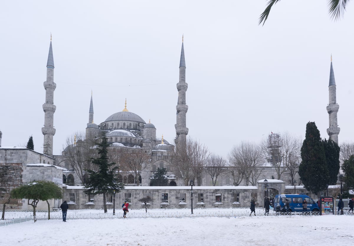 The Blue Mosque in Istanbul under snow, its minarets pale against a white winter sky